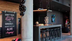 Zona de bar moderna con un letrero motivacional, barra, taburetes y decoración con luz de neón.