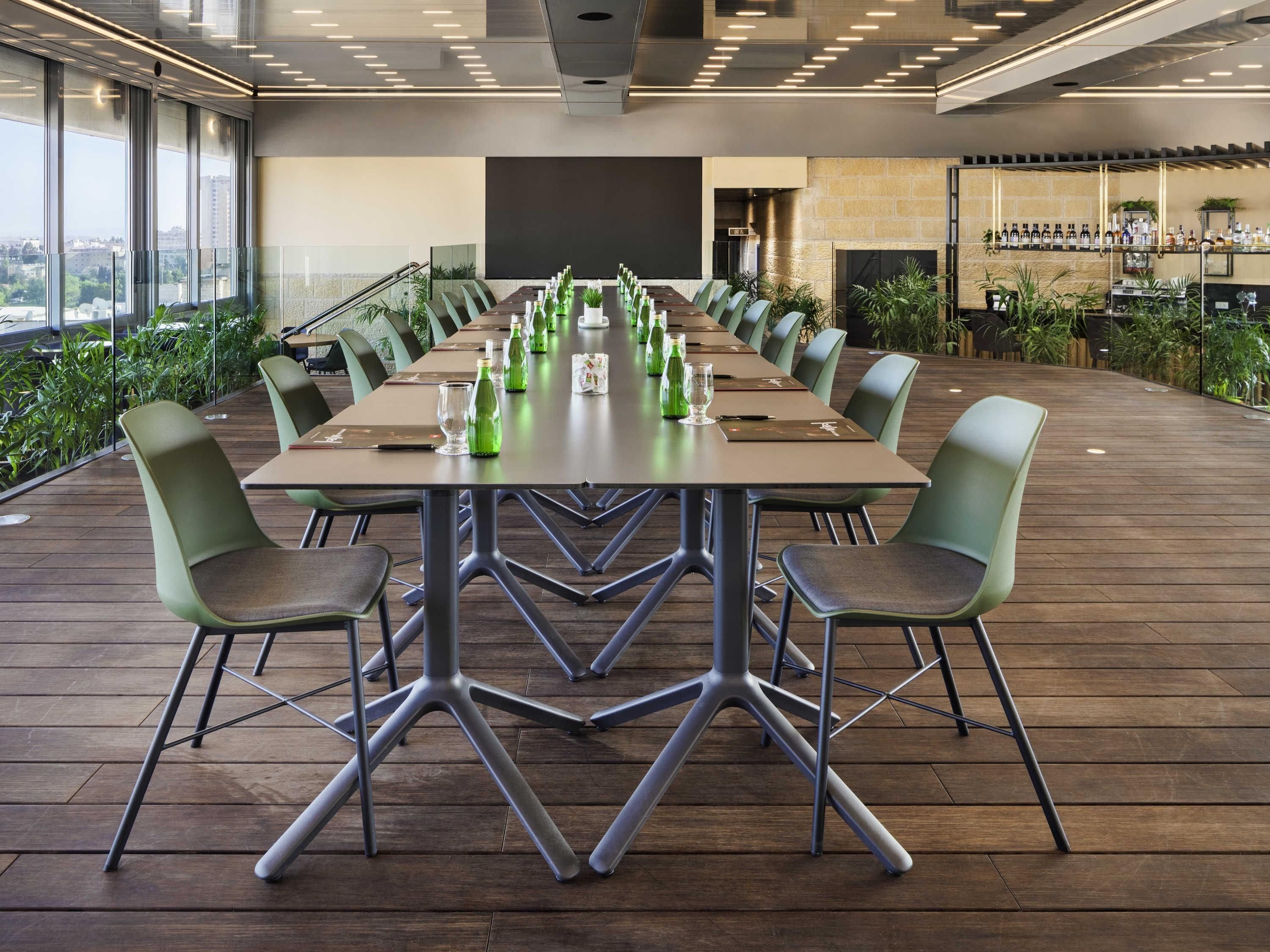 Un salón de conferencias con una larga mesa, sillas y una zona de bar con botellas.