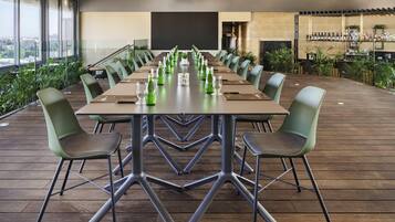 Un salón de conferencias con una larga mesa, sillas y una zona de bar con botellas.