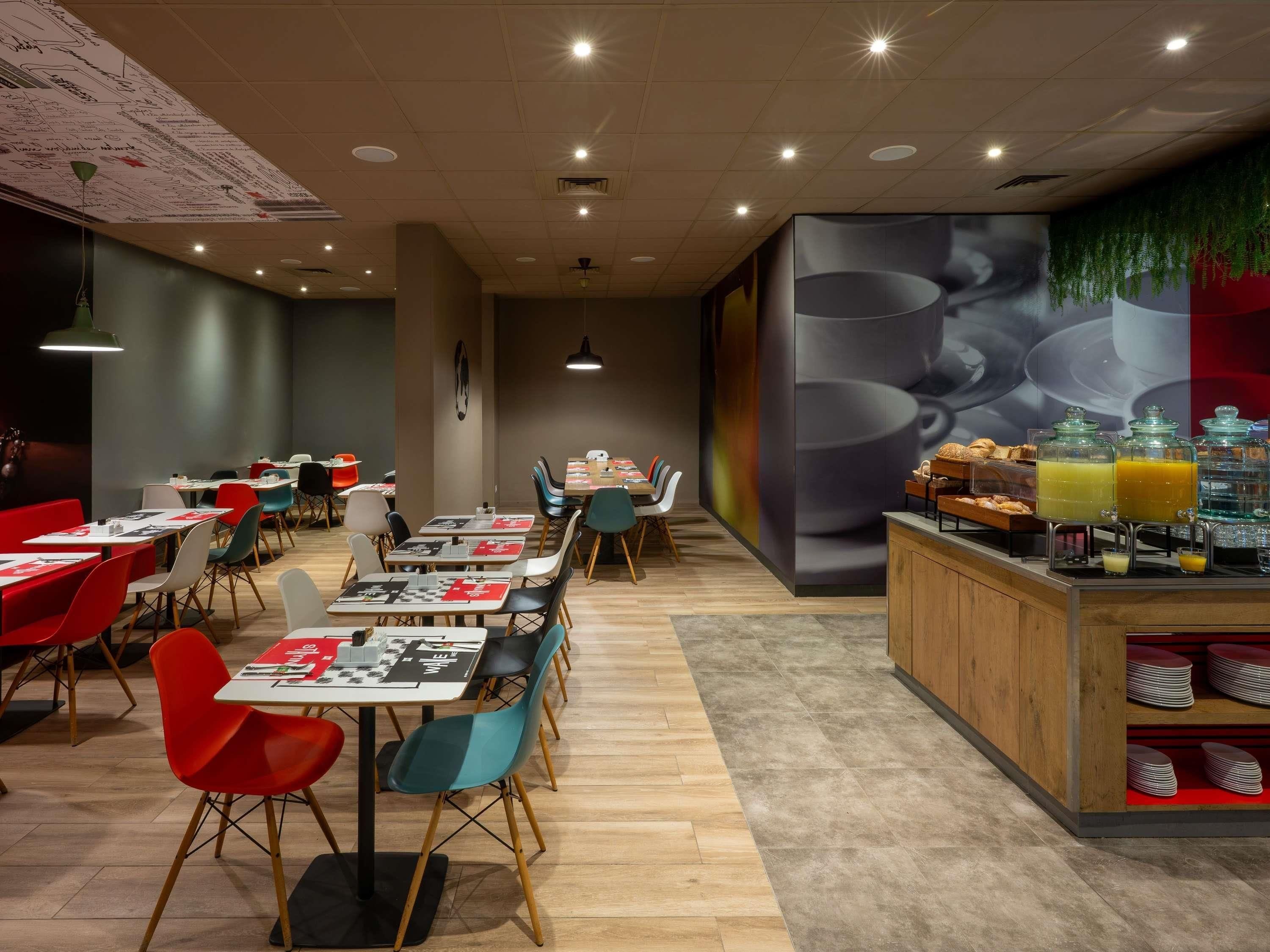 A modern cafe with tables and chairs, a coffee bar, and a mural on the wall.
