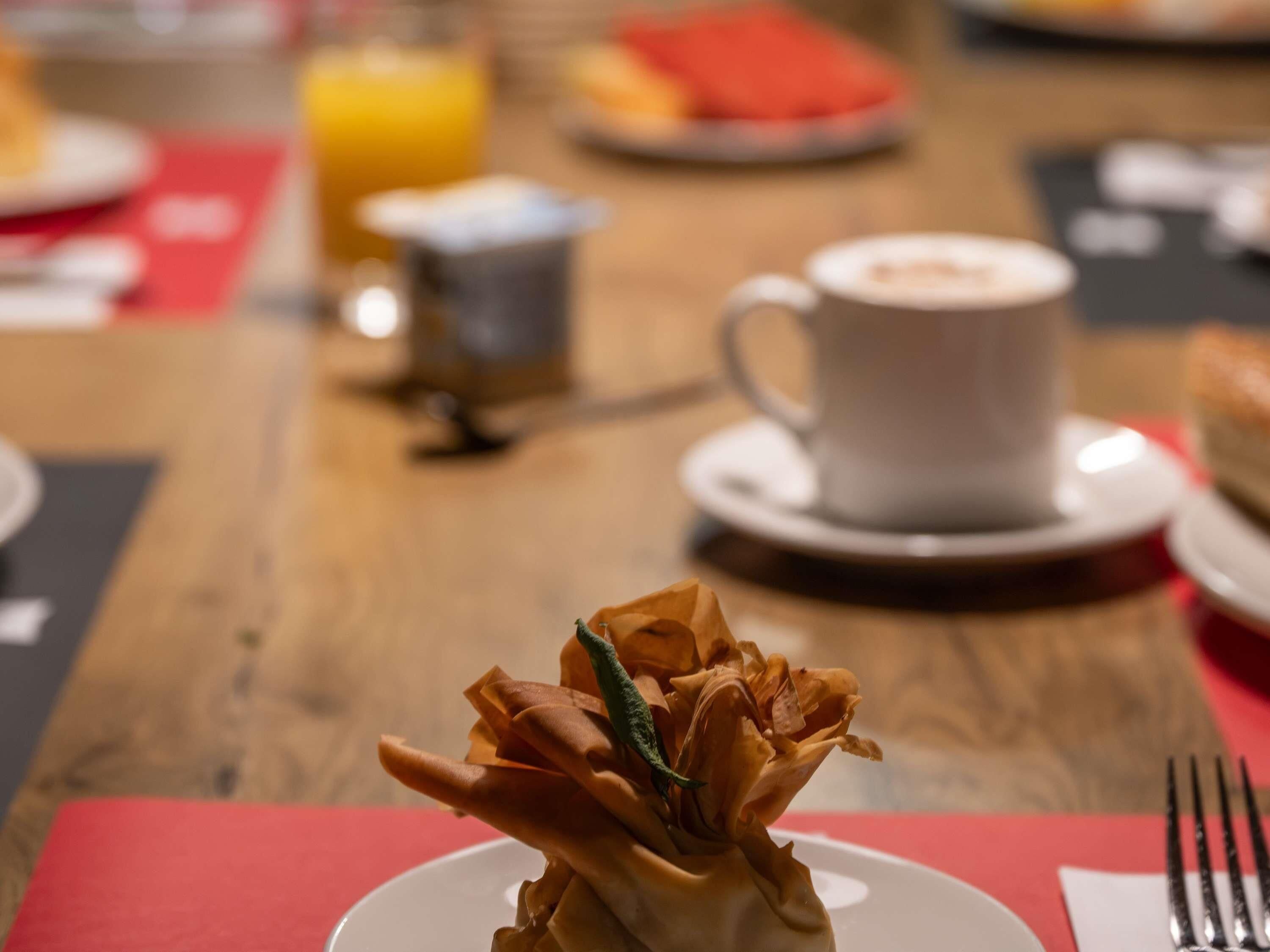 A dining table with a plate of food, a cup of coffee, and a glass of orange juice.