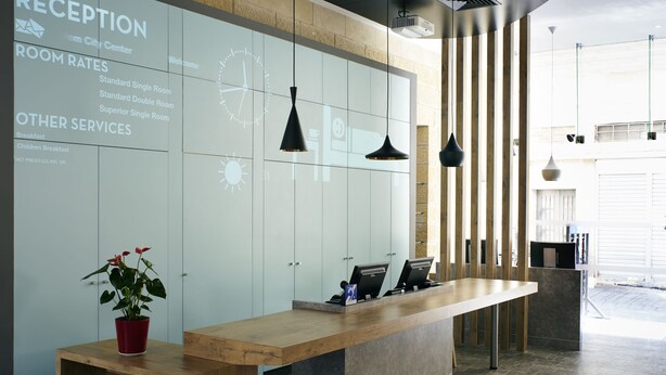 Zona de recepción con mostrador, un reloj y una pared mostrando tarifas y servicios.