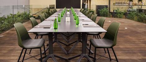 A conference room with a long table, green chairs, and a bar area with bottles.