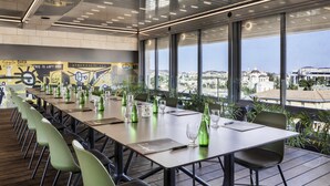 Un salón de conferencias con una larga mesa, sillas y vistas a la ciudad.
