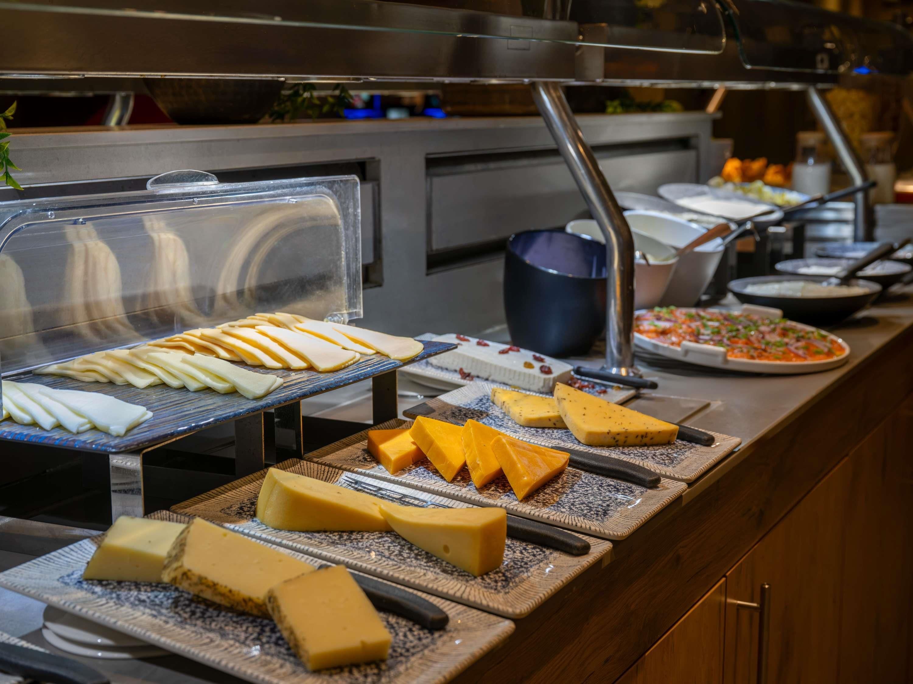 A buffet with various cheeses and a pizza.