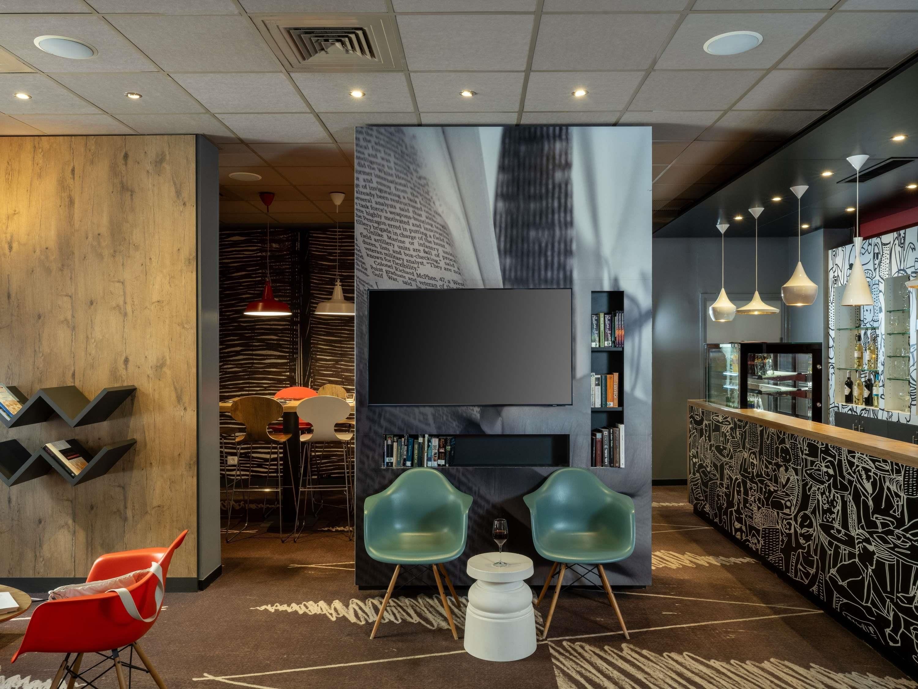 A modern interior with a flat-screen TV, bookshelves, a bar area, and a seating arrangement.