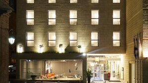 A multi-story hotel with uniformly lit windows, a ground-level entrance with a reception desk, and a visible outdoor seating area.
