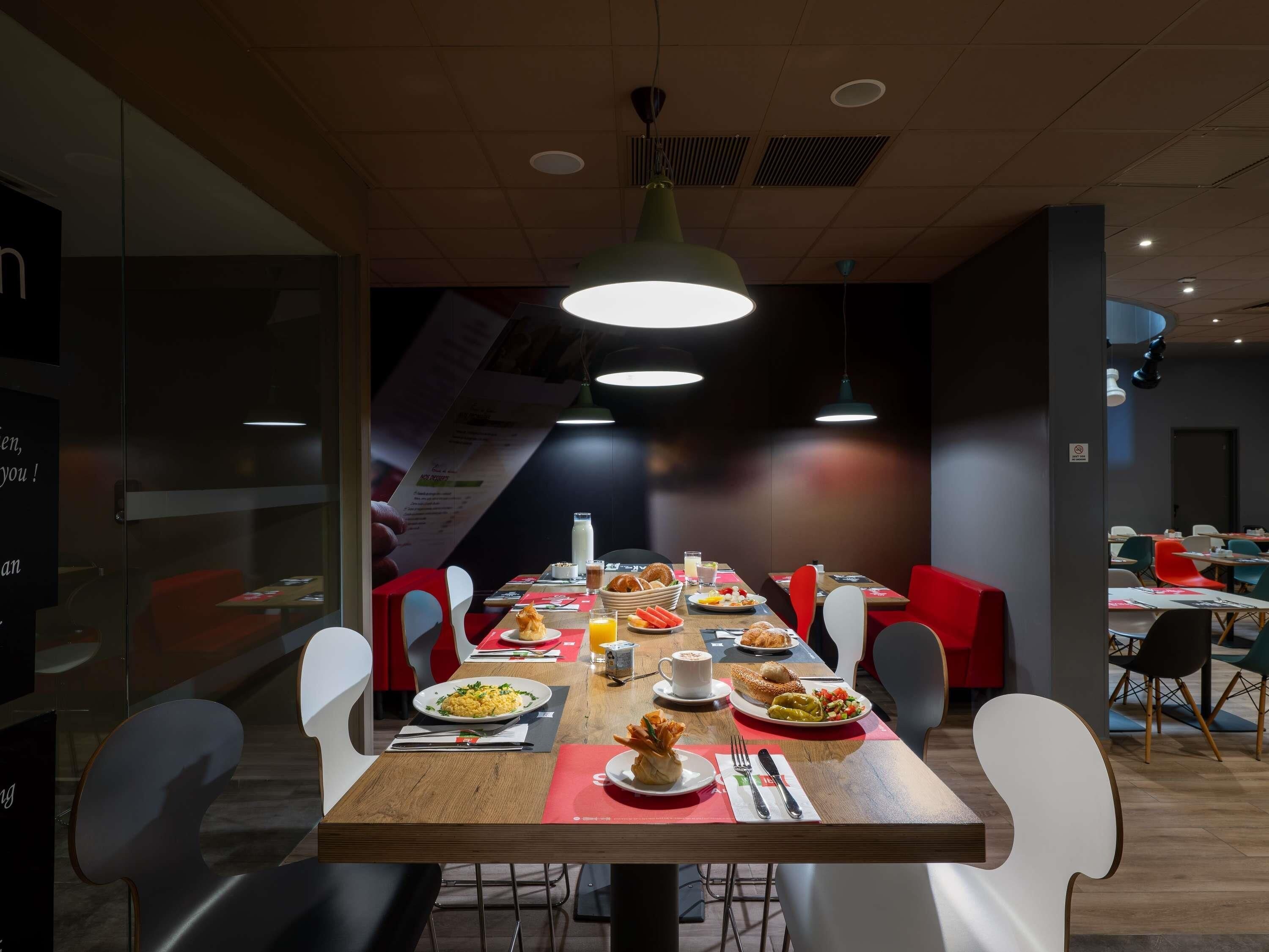 A modern dining area with a long table set for a meal, surrounded by chairs.