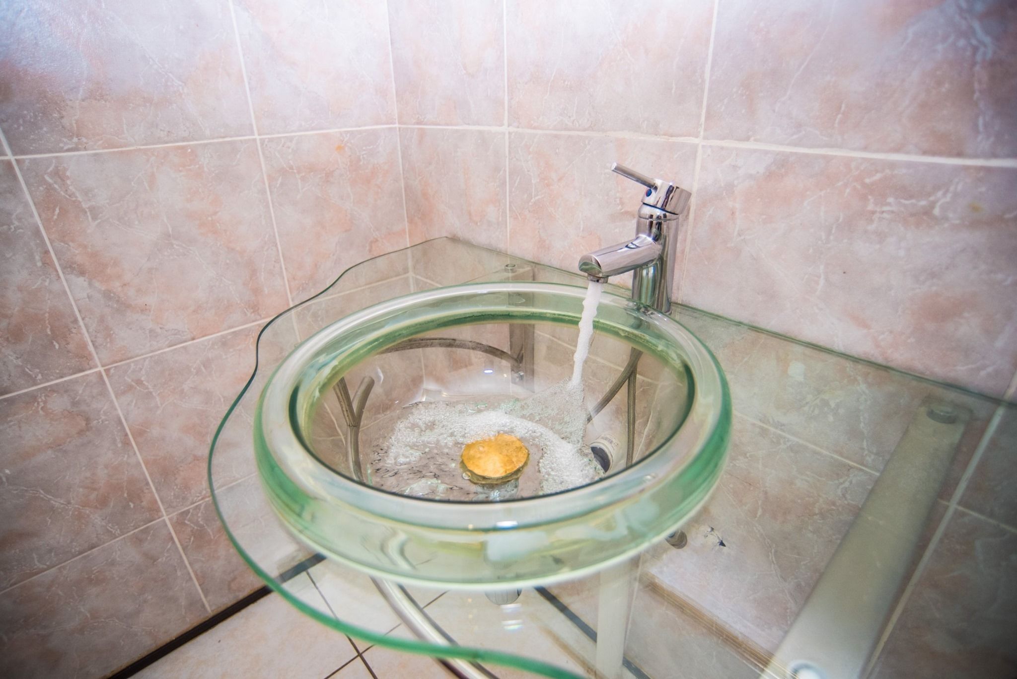 Des toilettes en forme de bol en verre, avec un robinet et de l’eau courante.