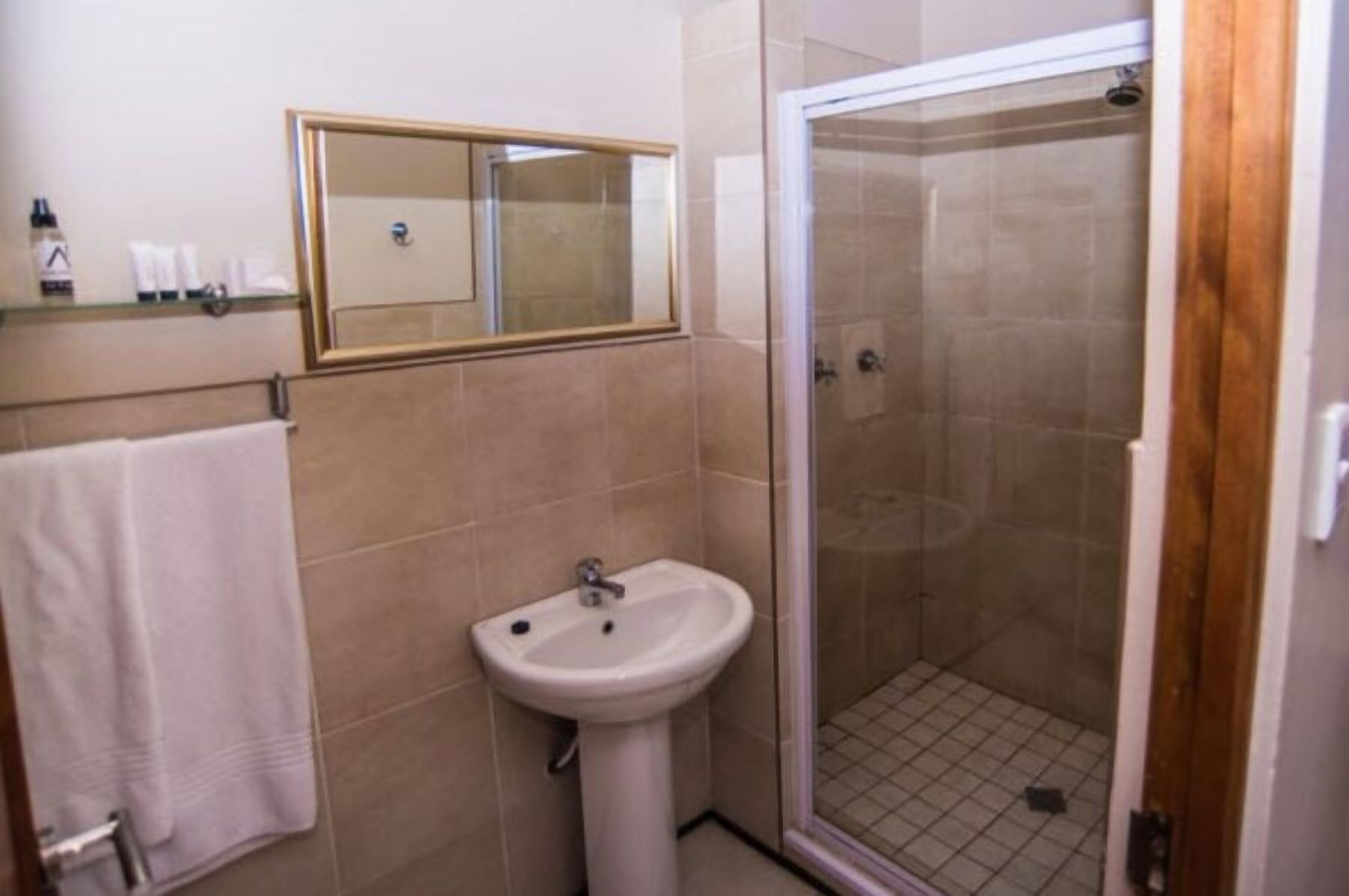 A bathroom with a sink, mirror, and shower.