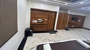 Habitación de hotel con cama, armario de madera, una mesita con artículos de aseo y televisor.