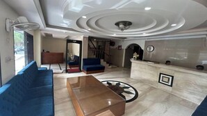 Amplia sala de estar con un sofá azul, una mesa de centro de madera y un mostrador de recepción de mármol.