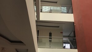 Un atrio de varios niveles con barandillas de vidrio y un techo alto.