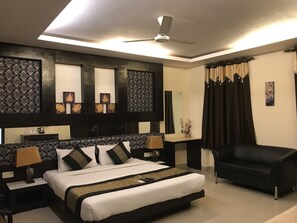 Una moderna camera d'albergo con un letto grande, una poltrona nera, una ventola a soffitto e pannelli decorativi a parete.