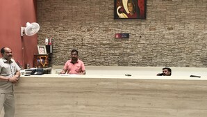 Un mostrador de recepción con un fondo de pared de piedra, una obra de arte enmarcada y un cartel que dice 'Photography Welcome'.
