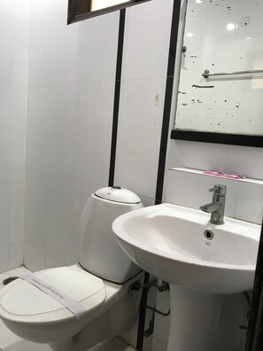 Un baño con inodoro, lavamanos y espejo.