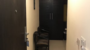 Un pasillo estrecho con una puerta oscura marcada “302”, una pequeña zona de estar con sillas a rayas y otra puerta oscura al final.
