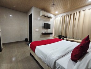 A hotel room with a bed, a TV mounted on the wall, and a window with curtains. - The Gera (New Delhi)