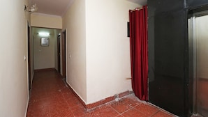 A narrow hallway with a red curtain and a black door, leading to a room with a tiled floor. - Royal Palce (new Delhi)