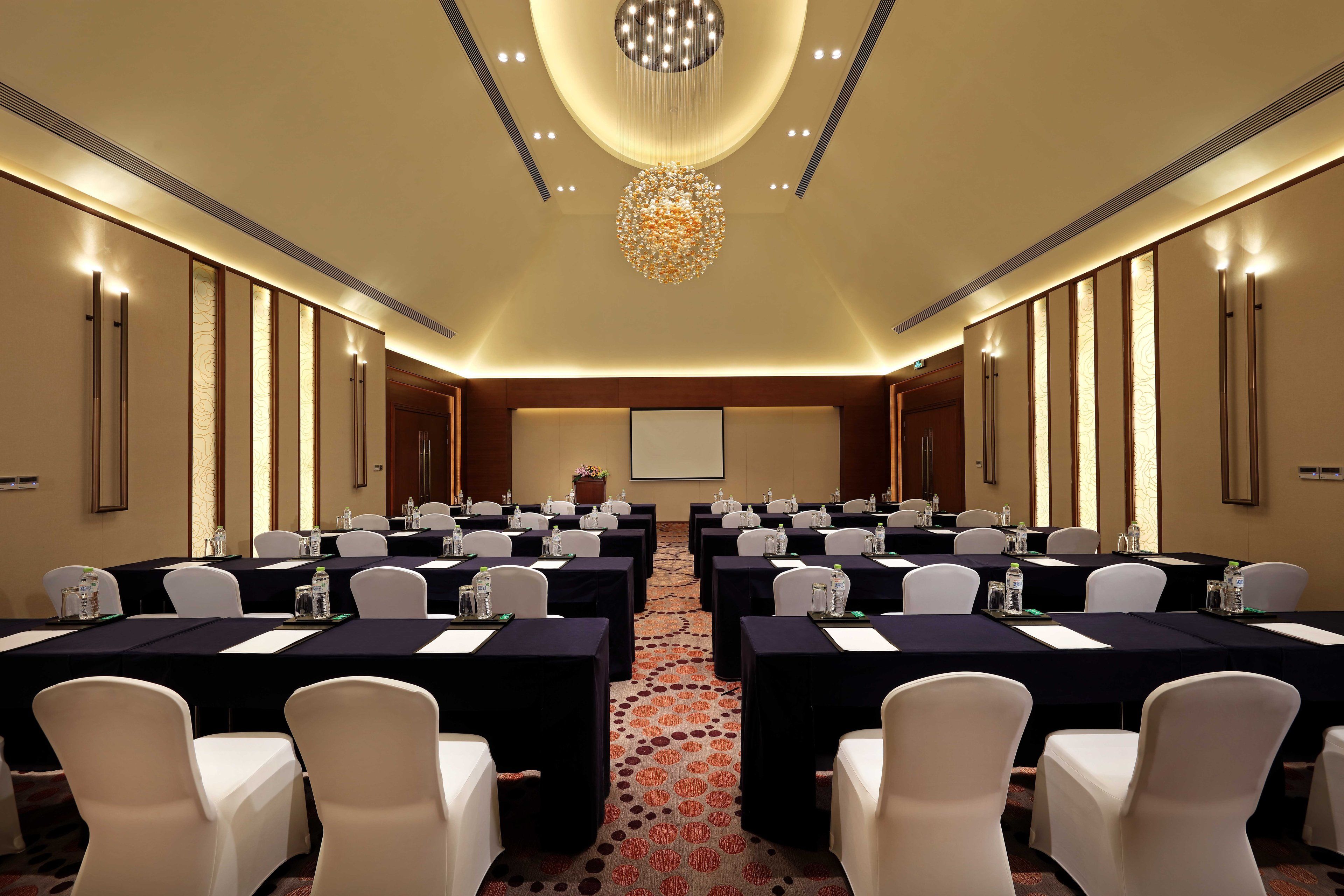 Une salle de conférence équipée de plusieurs tables, de chaises et d’un grand écran.