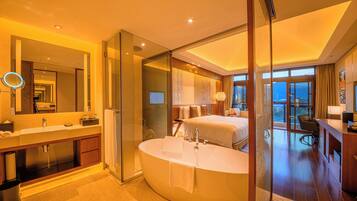 A modern hotel bathroom with a large bathtub, a separate shower area, and a glass-enclosed walk-in shower.
