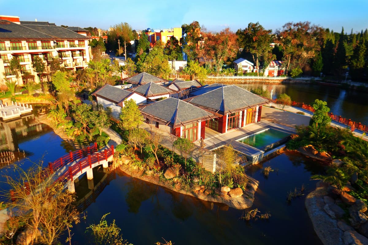A hotel with multiple buildings, a swimming pool, and a bridge over a body of water.