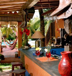 A tropical bar area with a hammock, a pool, and a rustic wooden structure. - Costa Linda Beach  (Paraguachi)