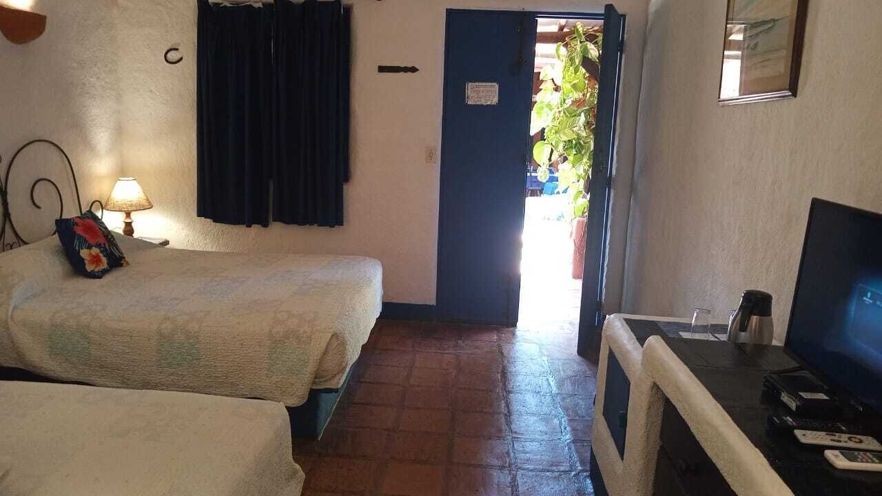 A room with two beds, a TV, and a door leading outside.