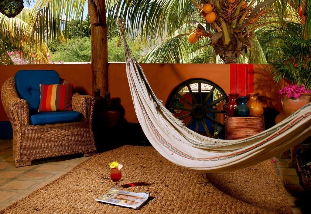 Una hamaca, un sillón de mimbre y una revista sobre un tapete tejido.
