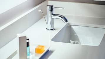 Un lavabo de salle de bain moderne, doté d’un robinet chromé, d’un distributeur de savon et d’un porte-brosse à dents.