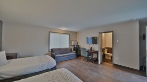 Cozy retreat with two single beds, a sofa, and a desk for work or relaxation.