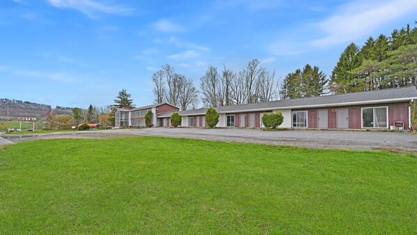 Situated on a grassy area, this motel features single-story buildings with large windows and a flat roof.