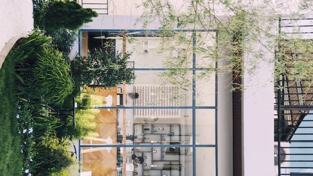 A modern building with a glass facade, a central open-plan office area, and surrounding greenery. - Phukaning Hotel (Udon Thani)