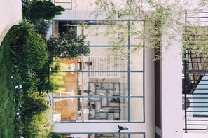 A modern building with a glass facade, a central open-plan office area, and surrounding greenery. - Phukaning Hotel (Udon Thani)