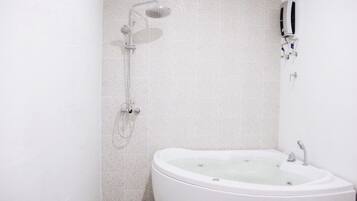 Un baño moderno con una bañera independiente, un cabezal de ducha manual y un grifo empotrado.