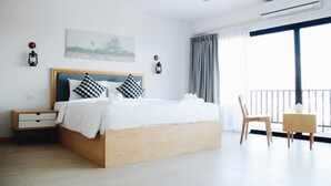 A modern hotel room with a large bed, a bedside table, a chair, and a balcony with a view. - Phukaning Hotel (Udon Thani)