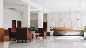 A modern lobby with a reception desk, seating area, and a large window. - Phukaning Hotel (Udon Thani)