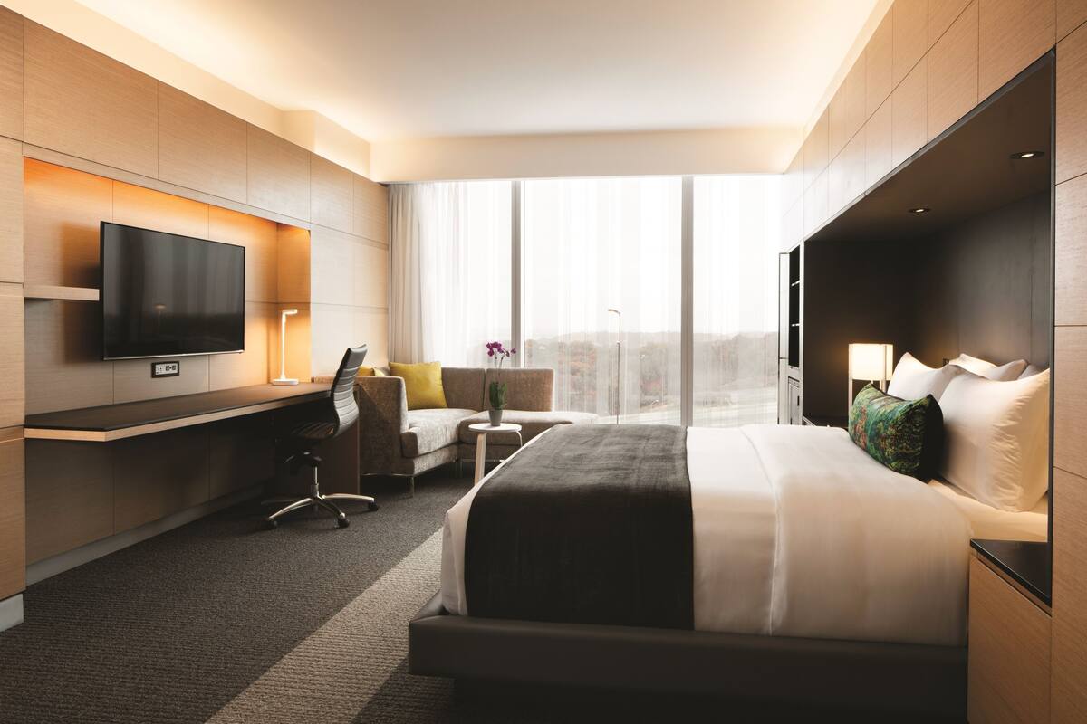 Une chambre d’hôtel moderne dotée d’un grand lit, d’un bureau, d’une télévision et offrant une vue sur la ville.