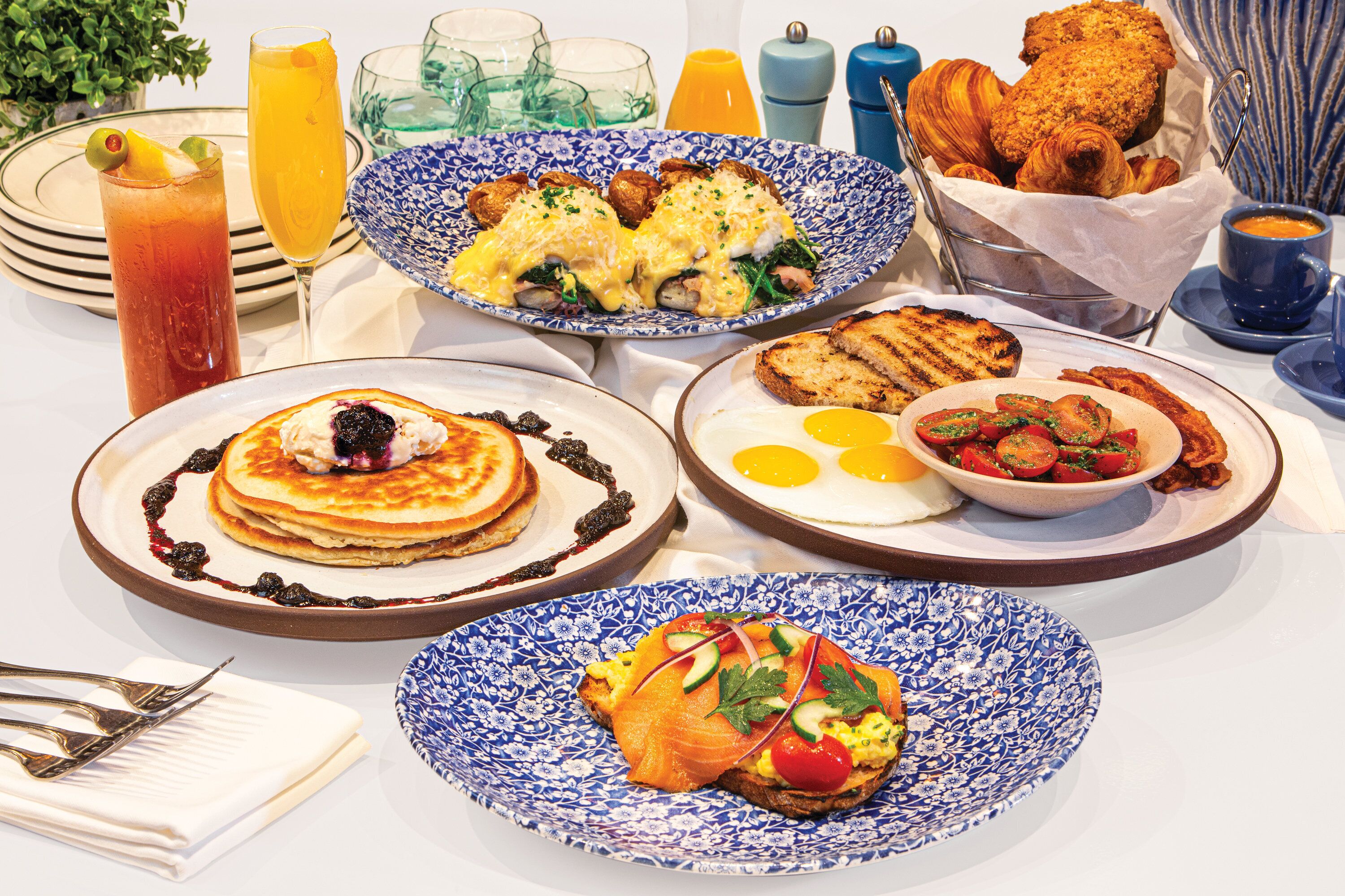 Ein reichhaltiges Frühstücksbuffet mit verschiedenen Speisen, darunter Pfannkuchen, Eier und Räucherlachs.