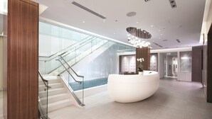 A modern lobby with a glass staircase, a reception desk, and a large white seating area. - MGM National Harbor Resort & Casino (Oxon Hill)