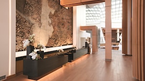 A modern reception area with a large abstract wall art, a reception desk, and a view of the interior space. - MGM National Harbor Resort & Casino (Oxon Hill)
