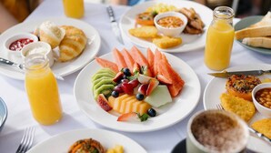 Un bufé de desayuno con diversos platos, incluyendo frutas, bollería y bebidas.