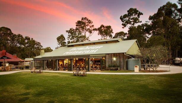 Un restaurante de estilo campestre con terraza y un césped cuidado.