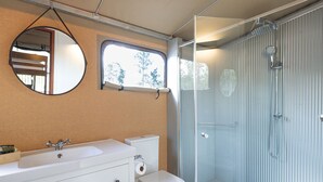Un baño con ducha de vidrio, lavabo blanco y retrete.