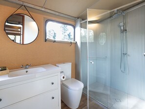 Un baño con ducha de vidrio, lavabo blanco y retrete.