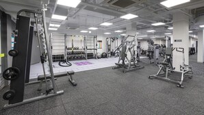 Une salle de sport équipée de divers appareils d’entraînement, notamment des appareils de musculation, des poids libres et des appareils de cardio.