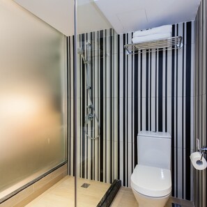 Casa de banho moderna com cabine de duche em vidro, sanita e design de parede riscado.