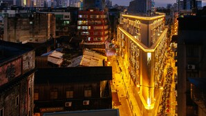 Une vue sur la ville au crépuscule, avec des bâtiments illuminés, une tour imposante et une rue bordée de motos garées.