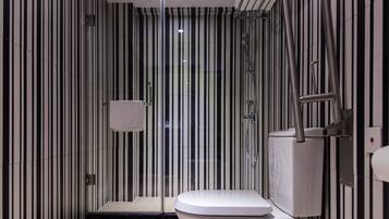A modern bathroom with a striped wall design, a white toilet, and a glass-enclosed shower area.