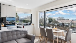 A modern kitchen with a dining area, large windows, and a view of the neighborhood. - 110 Hampden Apartments (Battery Point)